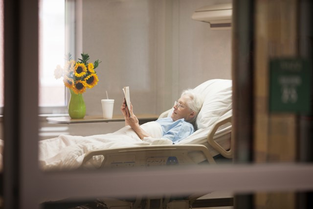 Elderly female patient reading a book in her bed