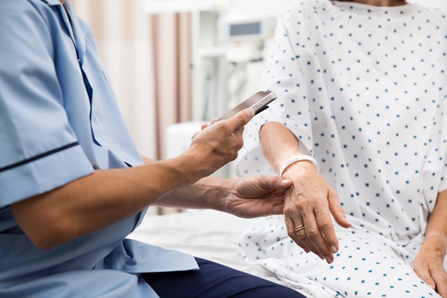 Close up detail of medical personnel scanning the barcode on a patient's wristband using a smart phone device