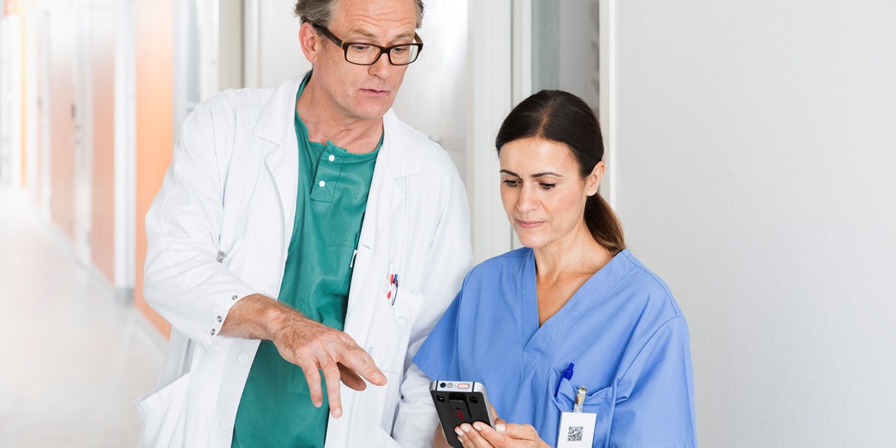 Doctor and nurse in scrubs using smart phone device together