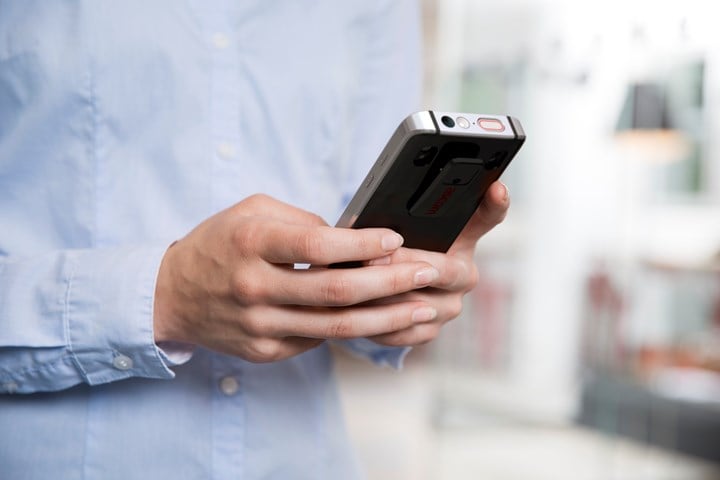 Close up of smart phone mobile device hand-held by person in light blue shirt