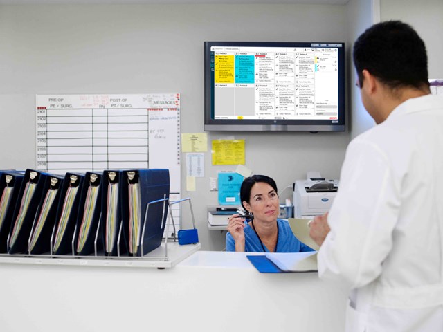 Doctor and nurse communicating in hospital reception with dashboard in the background