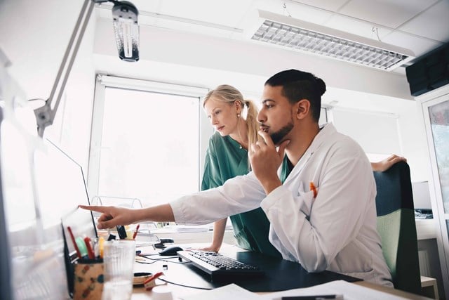 A man and woman nurse sitting at a desk in an office