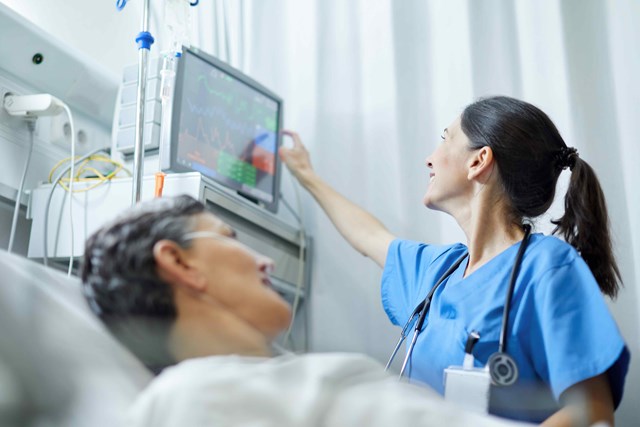 A nurse and patient in a hospital bed looking at a monitor