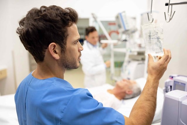 A male nurse with a patient in the background