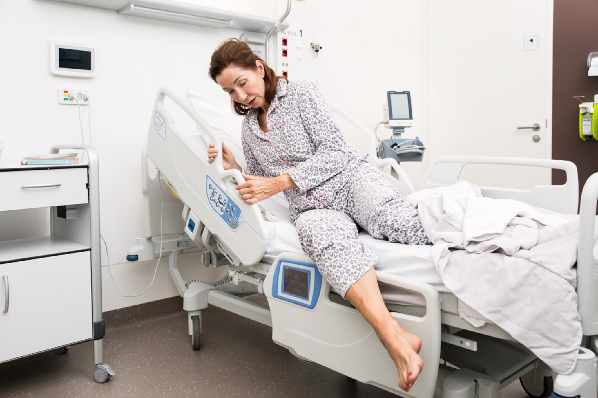 Female patient trying to get out of hospital bed