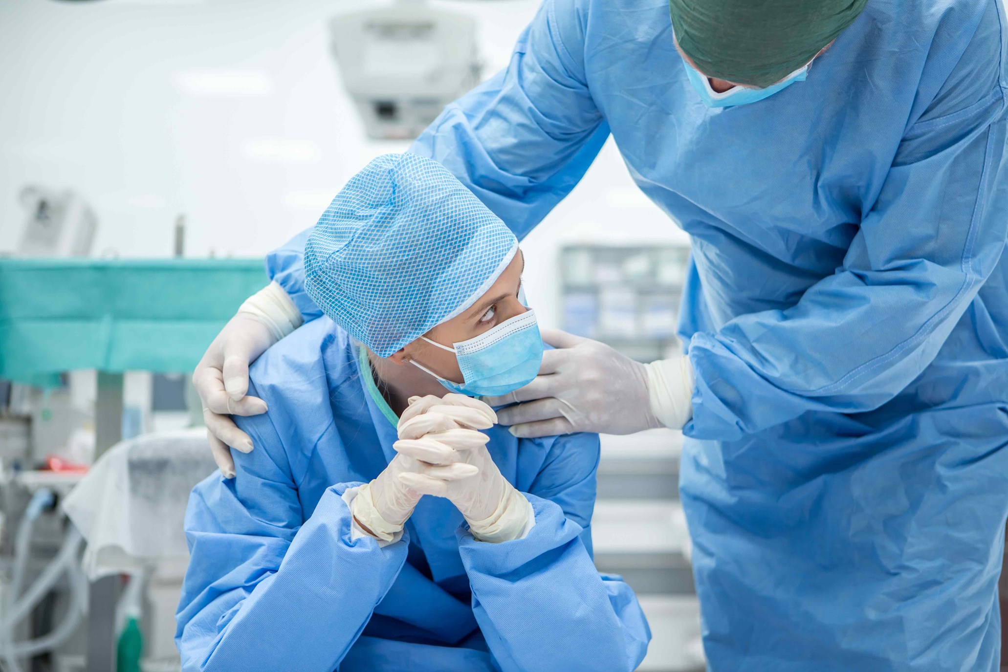 Detail of medical personnel in PPE in an operating room setup.