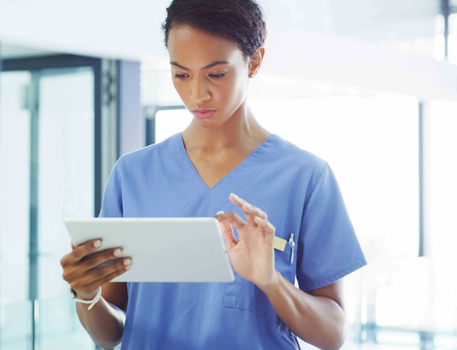Nurse wearing scrubs looking at tablet screen
