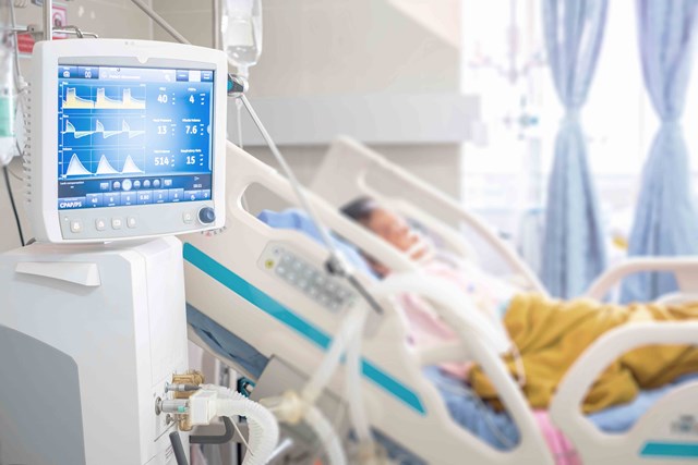 Blurred detail of patient resting in bed with vitals monitor in the foreground