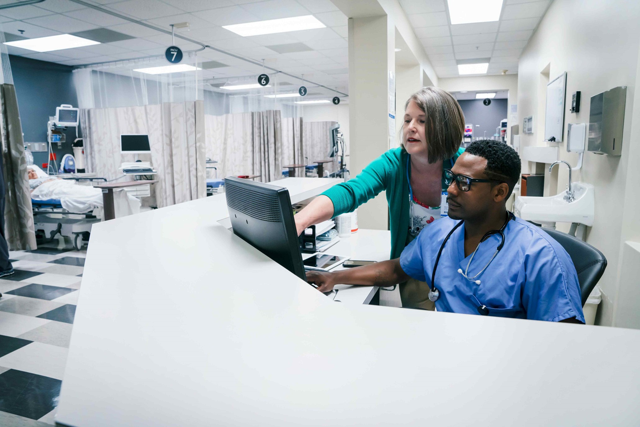 Manned nurse station with patient in the background.