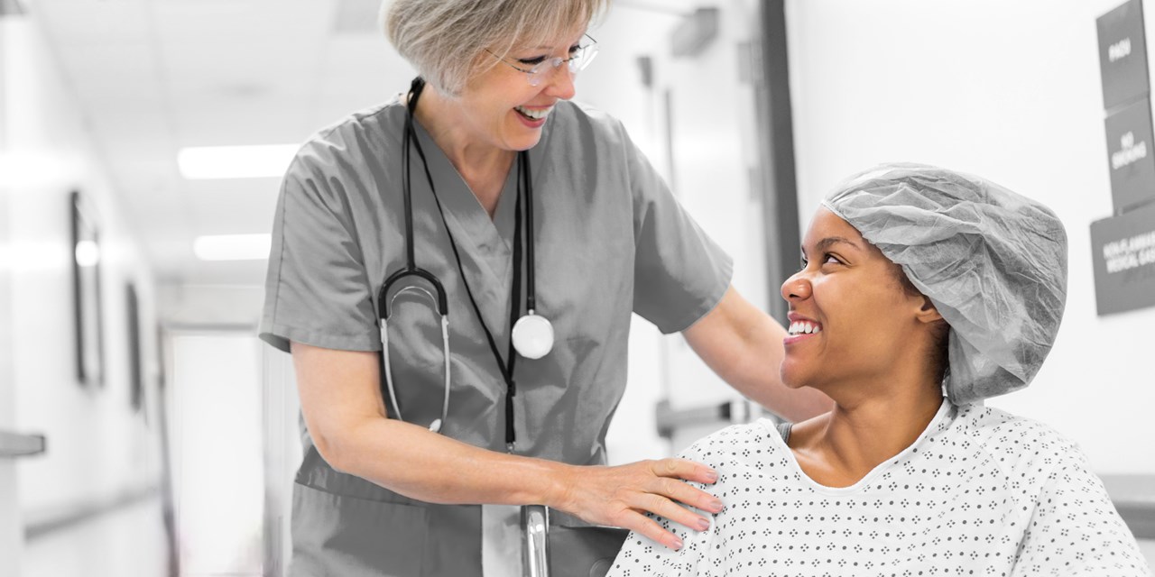 Female nurse and patient seated in a wheelchair in the hospital hallway