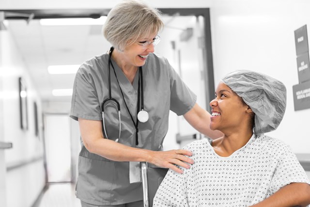 Female nurse and patient seated in a wheelchair in the hospital hallway