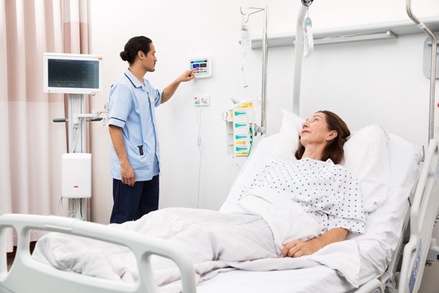 male clinician pressing nurse call button, telligence at bedside of patient