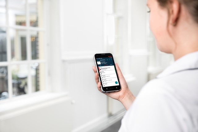 Close up of nurse holding and reading from device displaying something on screen