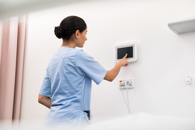 Female nurse entering information on a wall-mounted device