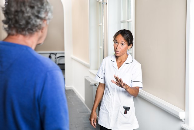 Nurse with phone in her pocket talking to a hospital visitor