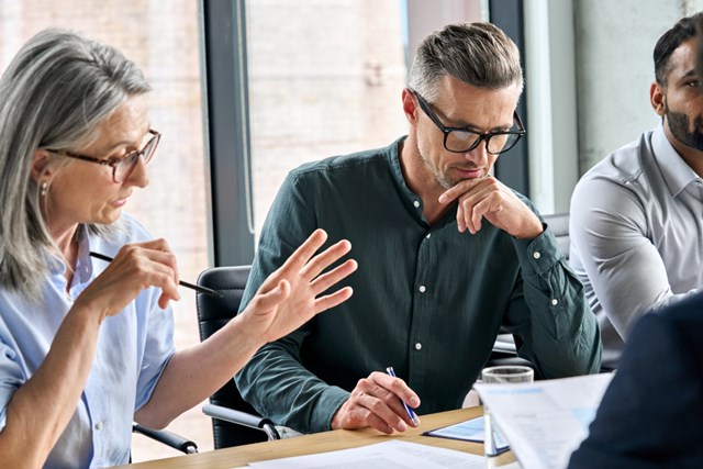 serious mature partners colleagues discussing at conference table