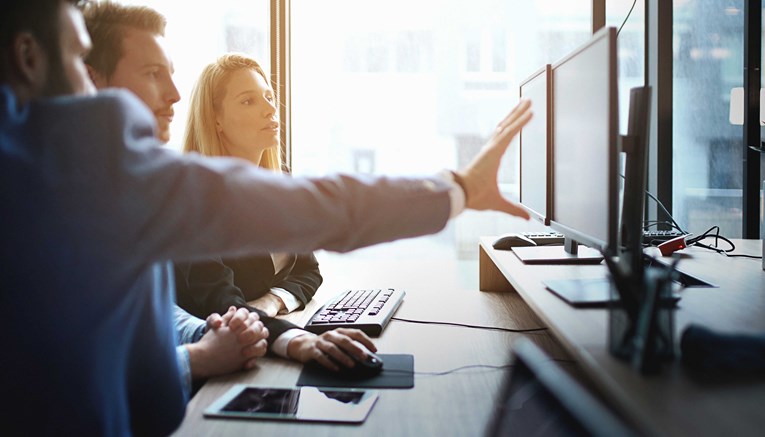 Team of two men and a woman brainstorming or collaborating in front of a computer screen