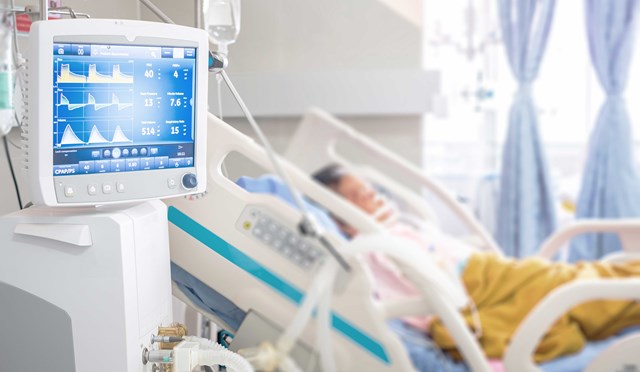 Blurred detail of patient resting in bed with vitals monitor in the foreground