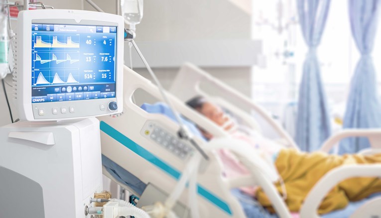 Blurred detail of patient resting in bed with vitals monitor in the foreground