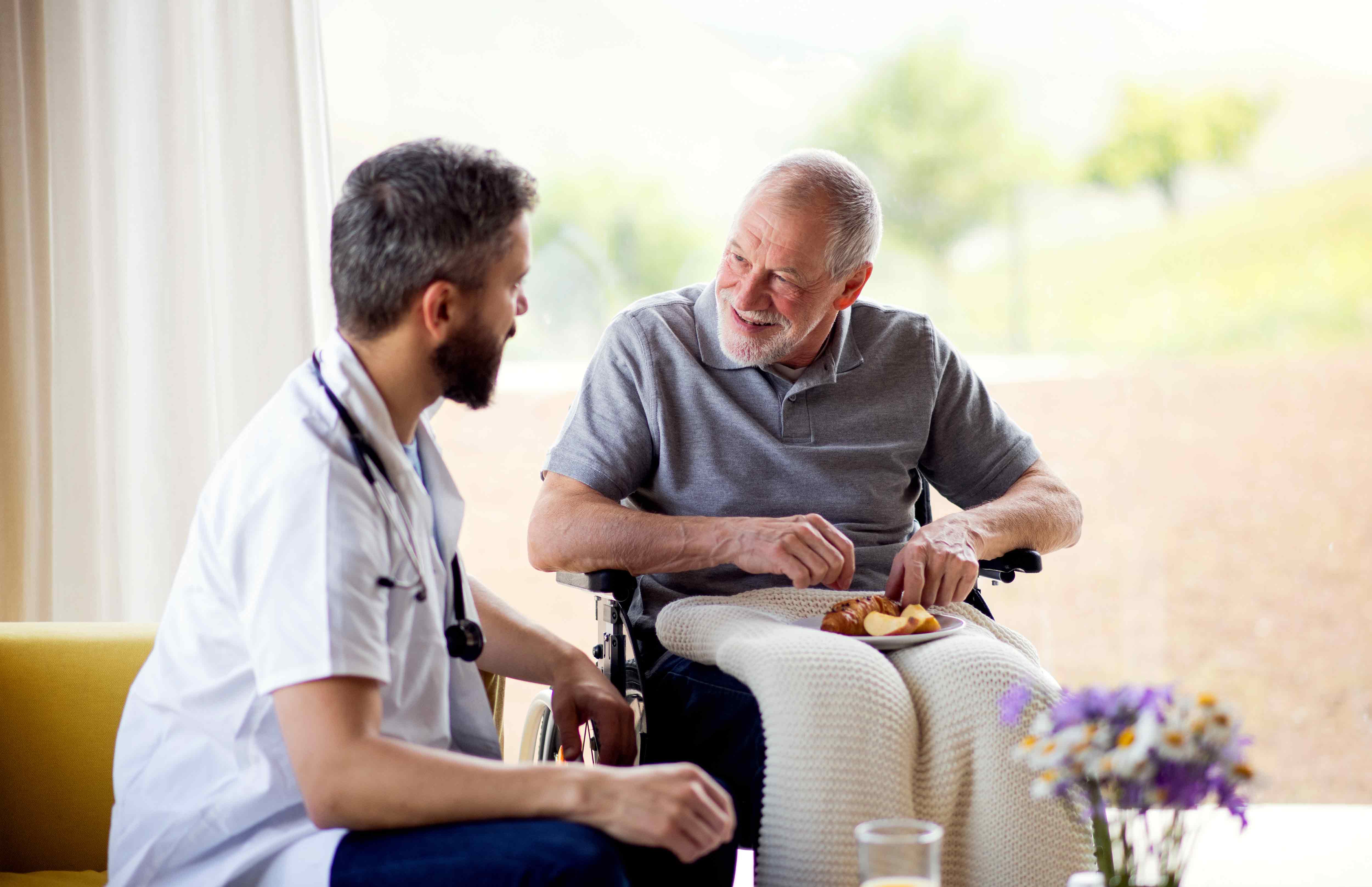 Male caregiver and male resident in wheelchair in senior care