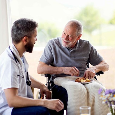 Male caregiver and male resident in wheelchair in senior care